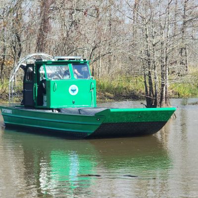 green military airboat out in swamp